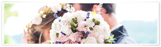 Hochzeitspaar mit Blumenstrauß in weiß im Vordergrund